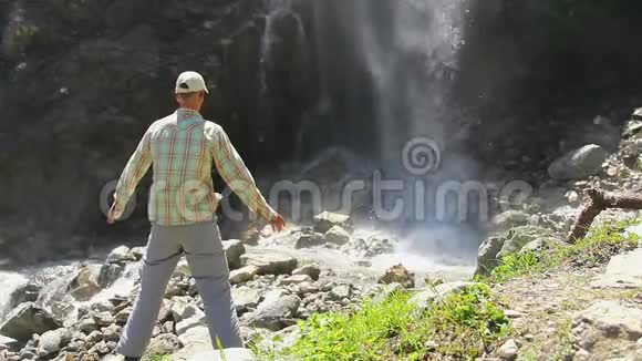 男游客站在瀑布脚下溅起水花视频的预览图