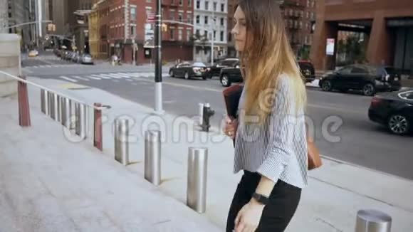 年轻漂亮的女商人走在美国纽约金融区看着手表慢动作视频的预览图