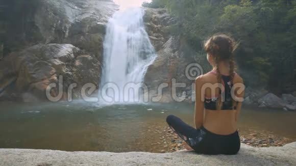石头上的女人欣赏瀑布美景视频的预览图