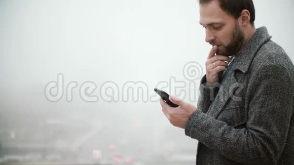 雾天站在法国巴黎埃菲尔铁塔的人英俊的男性使用带有触摸屏的智能手机视频的预览图