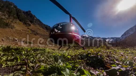 红色直升机停在草地上的山上视频的预览图