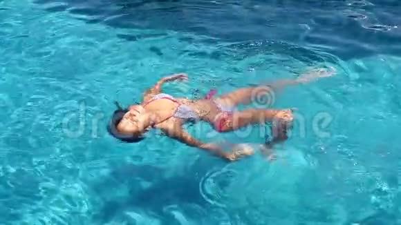 年轻的黑发女人在游泳池里游泳慢慢地放松1920x1080视频的预览图