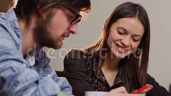 年轻的快乐男人展示了女人的智能手机微笑着聊天约会视频的预览图