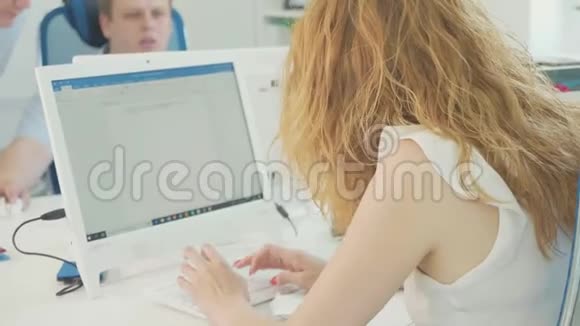 年轻女子在现代办公室的电脑键盘上打字视频的预览图