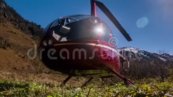 红色直升机停在草地上的山上视频的预览图