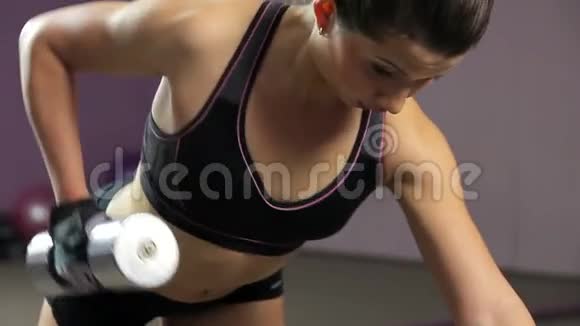 强壮的女运动员做单臂哑铃排操在健身房积极锻炼视频的预览图