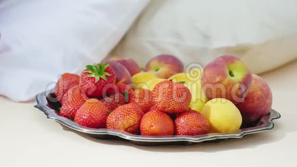 女人手选择美味的水果盘子站在枕头旁边床上的早餐和浪漫的浪漫视频的预览图