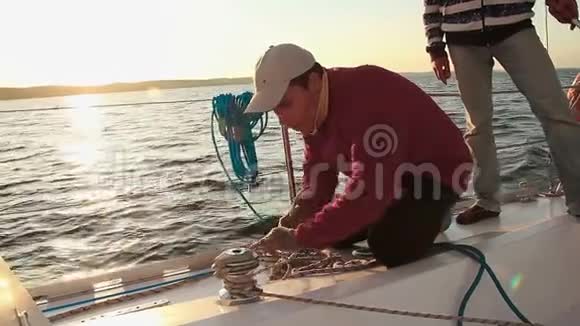 青年水手在帆船上系绳工作职业视频的预览图