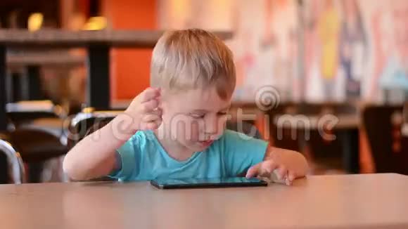 在咖啡馆里拿着平板电脑的男孩视频的预览图