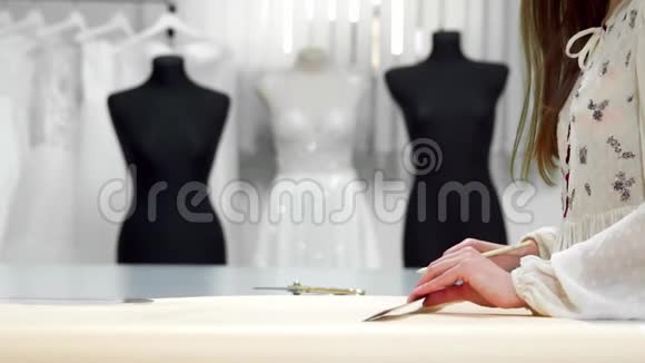 漂亮的女时装设计师用纸模板在穿着婚礼的人体模型上裁剪布料视频的预览图