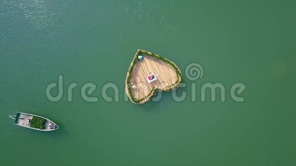 空中镜头小船在湖上游泳装饰花坛心形人们在漂浮中摇摆视频的预览图