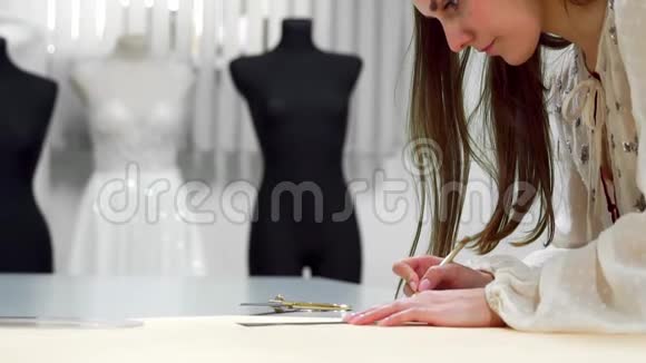 漂亮的女时装设计师用纸模板在穿着婚礼的人体模型上裁剪布料视频的预览图