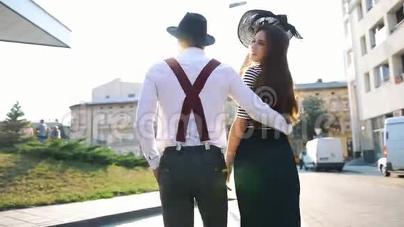 女人脱下帽子和一个男人一起在夕阳下沿街散步视频的预览图