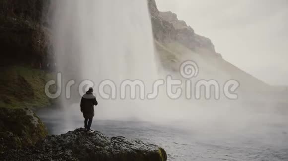 冰岛的Gljufrabui瀑布附近有动作摄像机的年轻游客看着北方自然的著名景象的人视频的预览图