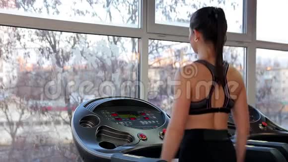 美丽的女士在跑步机上健步走为锻炼做热身运动视频的预览图