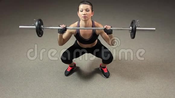 强壮肌肉的女士用杠铃做深蹲完成运动视频的预览图