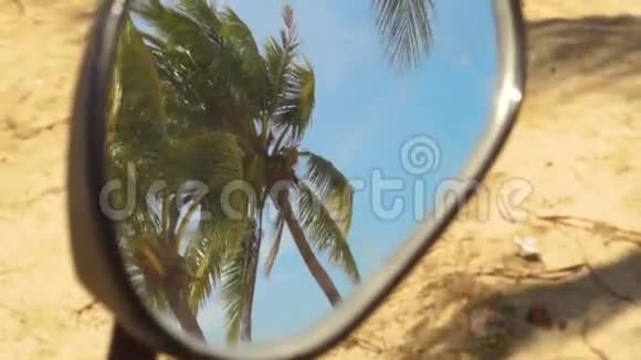 摩托车镜中绿色棕榈树在蓝天背景上的反射夏日海滩上的热带棕榈树视频的预览图
