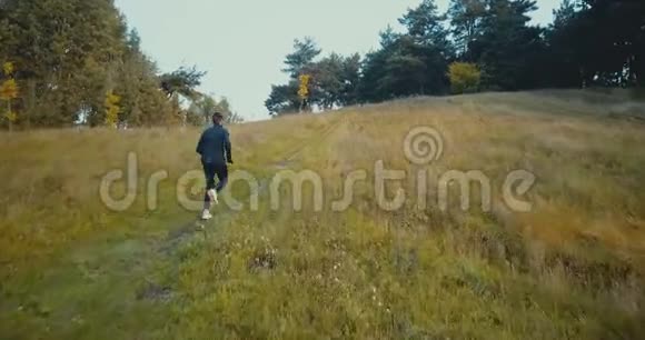 跑步者在通往森林的小路上上山无人机后视图年轻的耐力运动员跑越野跑视频的预览图