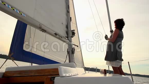女孩水手在帆船上看日落夏季活动视频的预览图