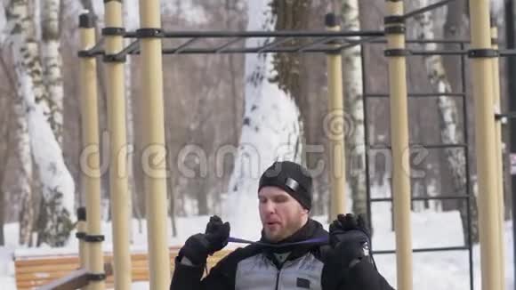 男子健美运动员在冬季公园运动场上做深蹲运动视频的预览图