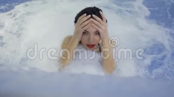 红唇迷人的女人在游泳池里享受水流视频的预览图