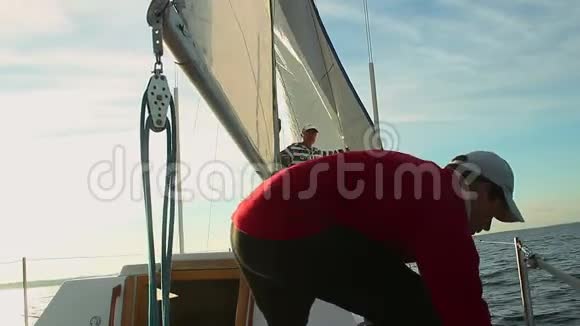 年轻的男水手在帆船上帮助高级船长视频的预览图