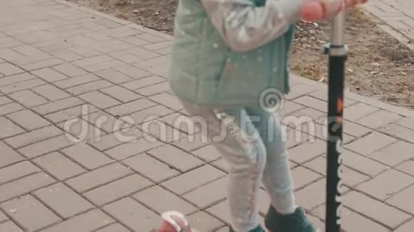 小女孩骑着粉红色的滑板车在人行道上骑着斯洛莫的科普空间视频的预览图