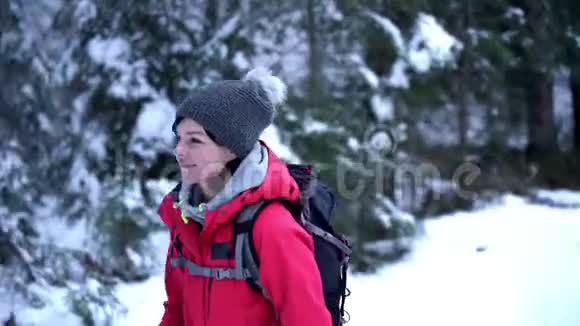 年轻的白种人妇女在白雪覆盖的树林里徒步旅行回头看视频的预览图