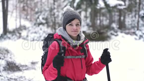 年轻的白种人妇女在白雪覆盖的树林里徒步旅行回头看视频的预览图