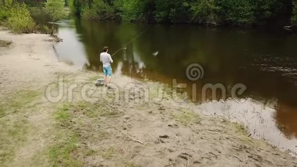 江岸钓竿的渔夫鸟瞰图渔夫钓到一条鱼农村逃亡的概念视频的预览图