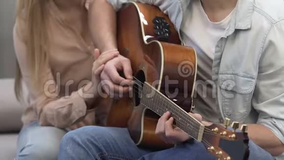 年轻女子一边弹吉他一边握着男朋友的手浪漫温柔视频的预览图