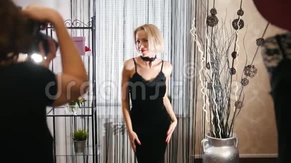 时尚的金发女郎身着鸡尾酒礼服在服装精品店为摄影师摆姿势视频的预览图