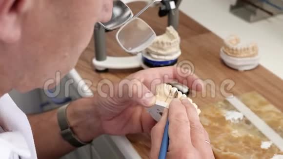 在实验室工作场所牙科技师在牙齿假体上绘制白色陶瓷釉视频的预览图