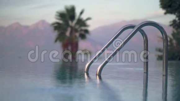 开放的游泳池棕榈树和高山上有闪亮的栏杆视频的预览图