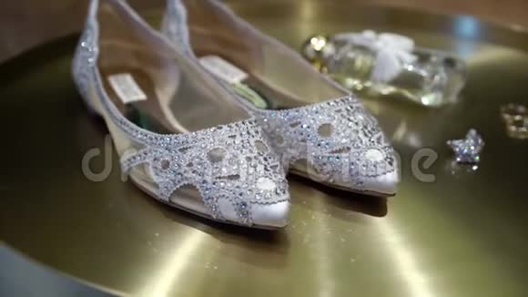 金色背景上有彩纸和珠宝耳环的新娘婚礼鞋视频的预览图