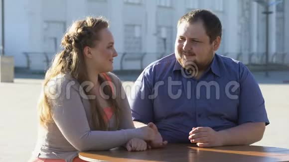 年轻人抚摸女朋友的手在户外咖啡馆浪漫约会亲密无间视频的预览图