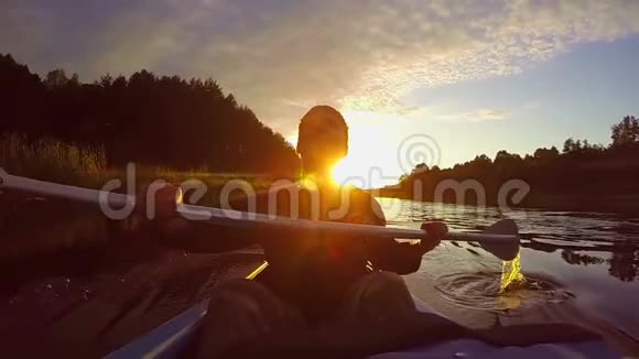 日落时分年轻快乐的男子划着皮划艇的剪影视频的预览图