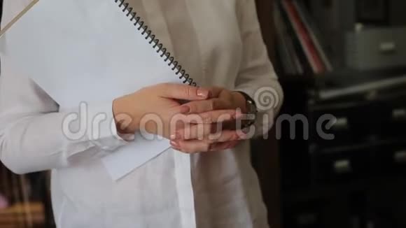 穿白衬衫的女人拿着日记视频的预览图