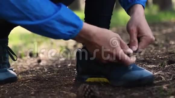 人在森林道路上奔跑时系鞋带在森林里用手系鞋带的特写镜头视频的预览图