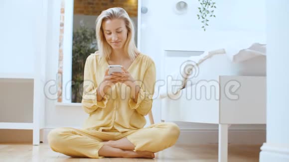 年轻的金发女人坐在地板上打电话视频的预览图
