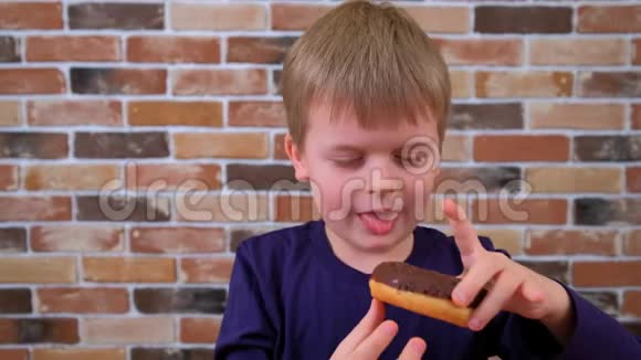 小可爱的男孩在砖墙背景上微笑着吃甜甜圈视频的预览图