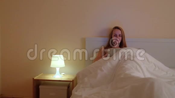 快乐的休闲美女在床上用笔记本电脑工作视频的预览图