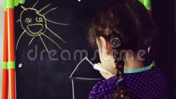 一个小女孩用彩色蜡笔在马尔伯特上画了一个梦幻的房子视频的预览图