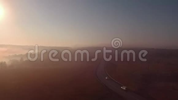 雾蒙蒙的日出和汽车的轮廓公路慢动作视频的预览图