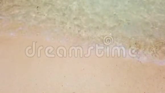 在白沙滩和清澈的海水上挥动白色泡沫可用作暑假背景视频的预览图