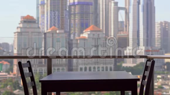 年轻的女家庭教师在阳台上准备早餐俯瞰市中心的摩天大楼视频的预览图