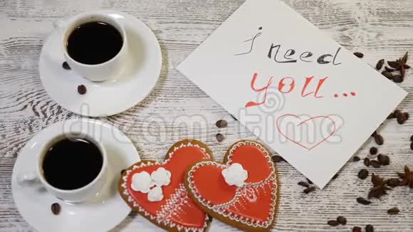 我需要你的留言条和两杯带有心形姜饼干的咖啡在木桌上的俯视图爱情视频的预览图