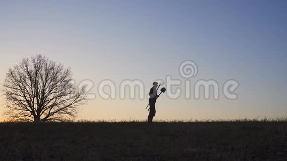 一个满意的农民在田里跳舞田野里日落或日出的剪影视频的预览图