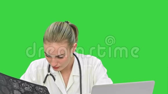 年轻的女医生检查X射线写下结果诊断到笔记本电脑上的绿色屏幕铬键视频的预览图