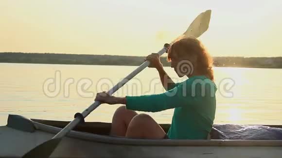 日落时分红发少女划着皮划艇体育旅游视频的预览图